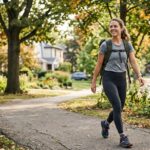 Mom doing rucking outdoors with a weighted backpack to support running strength and endurance